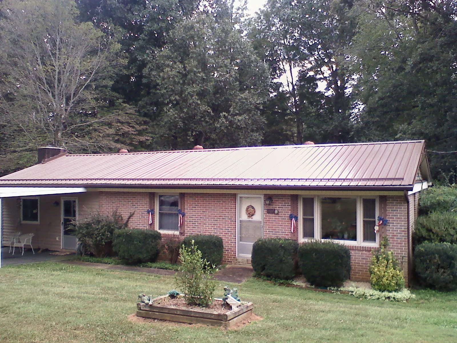 Bronze metal roof on a brick ranch home with a carport in Gaines