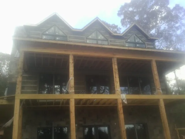 Dormers and porch framing on a large log home under construction — Roof Coating work by our crew in Gaines
