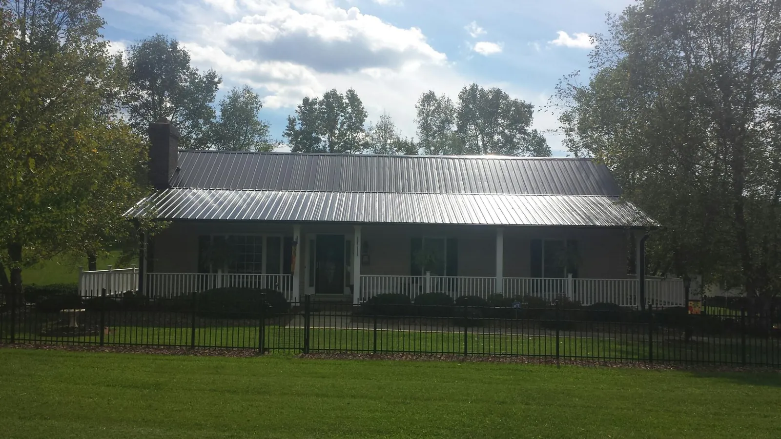Gray metal roof on a brick ranch with a full width front porch — Gutter Guard Installation work by our crew in Gaines