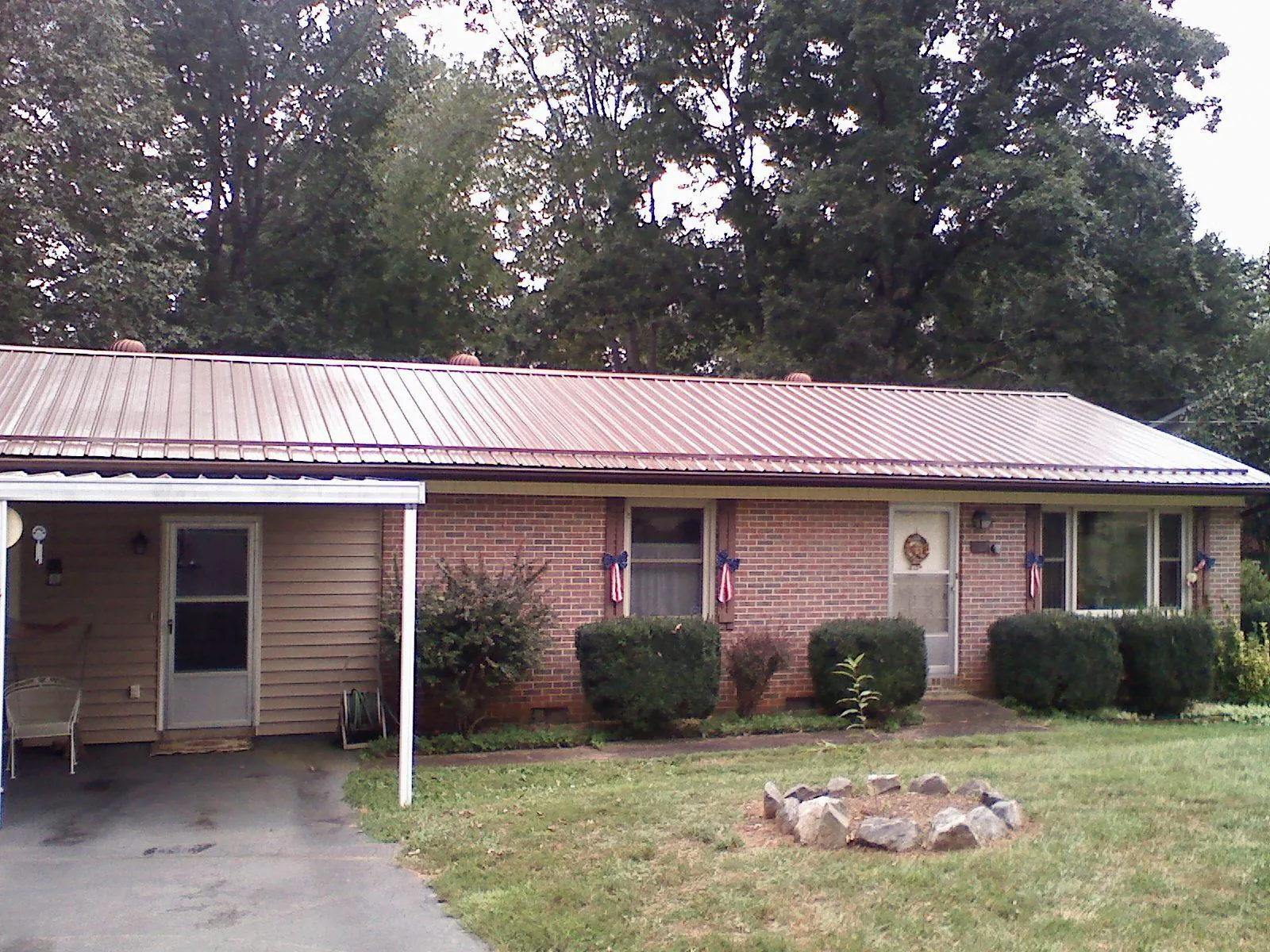 Bronze metal roof and carport on a brick ranch home — Roof Repair work by our crew in Gaines