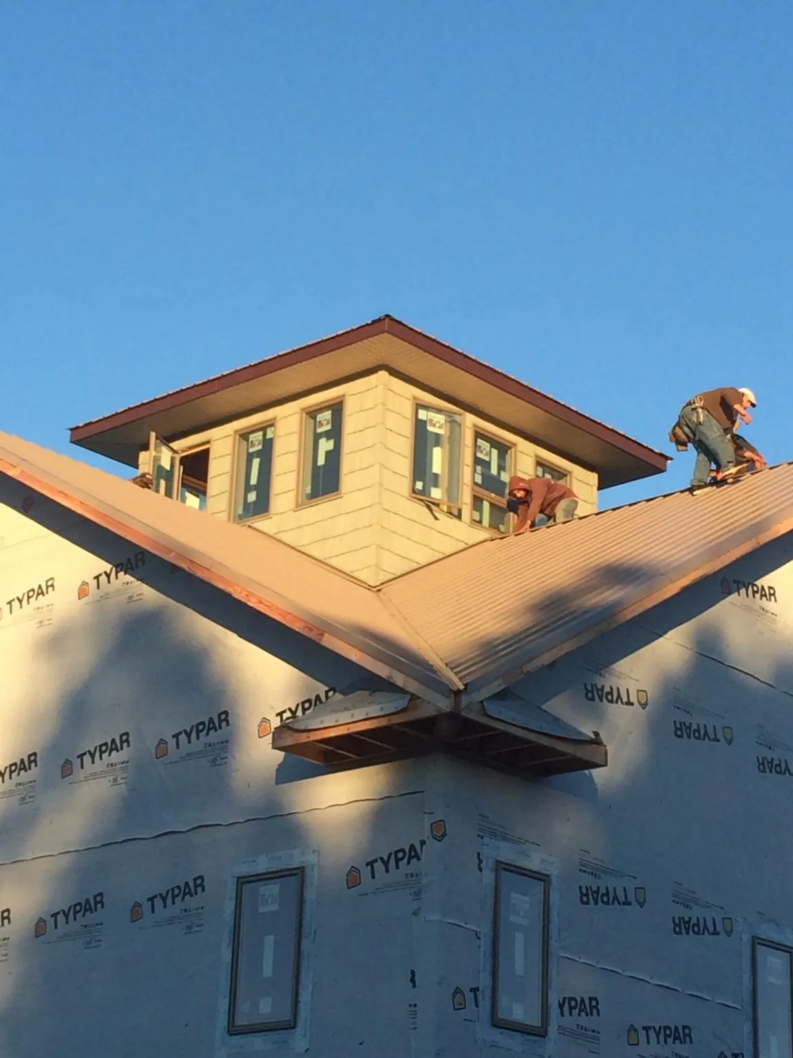 Roofers working around a rooftop cupola on a new metal roof at sunset — Roof Waterproofing in Gaines by Roofing Brothers